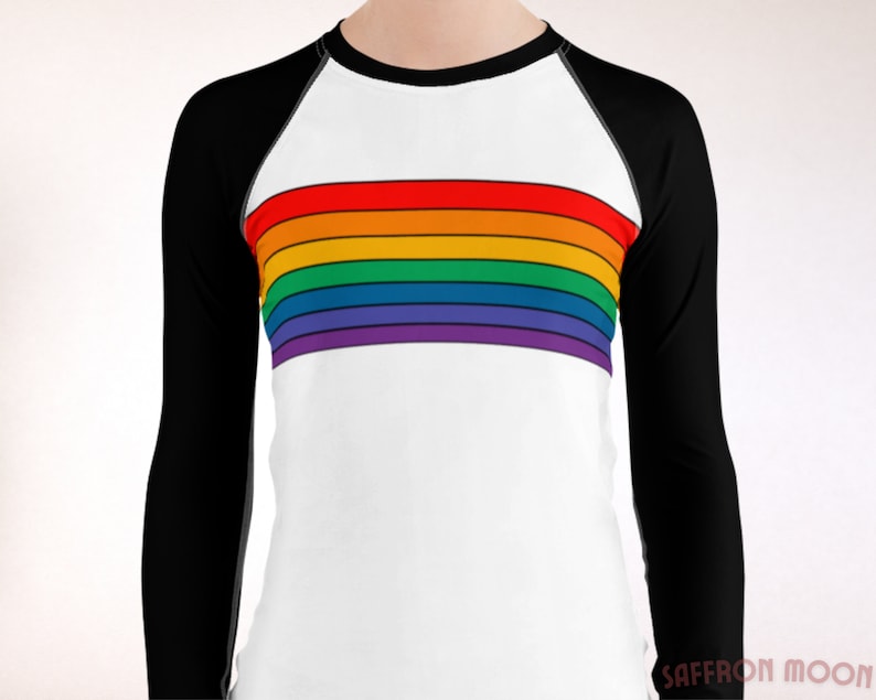 May include: A white long-sleeve shirt with black raglan sleeves and a rainbow stripe across the chest. The shirt has a crew neck.