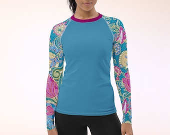 Puede incluir: Una camisa de manga larga con un cuerpo azul turquesa y un estampado floral colorido en las mangas. El estampado floral es en tonos de rosa, azul, amarillo y verde.