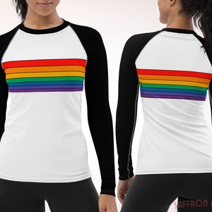 May include: A white long-sleeve shirt with black sleeves and a rainbow stripe design across the chest. The shirt is made of a stretchy, moisture-wicking fabric.