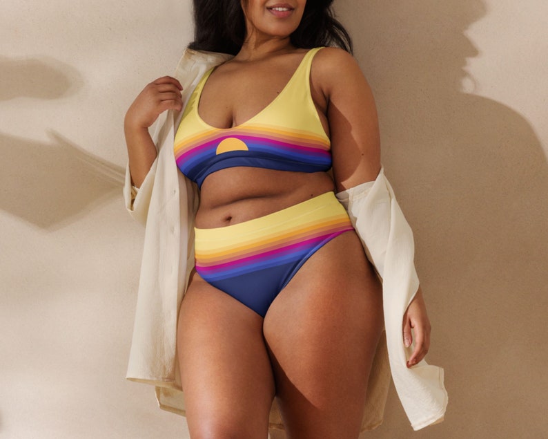 May include: A yellow and blue striped bikini with a sunset graphic. The top is a scoop neck style and the bottom is a high-waisted style.