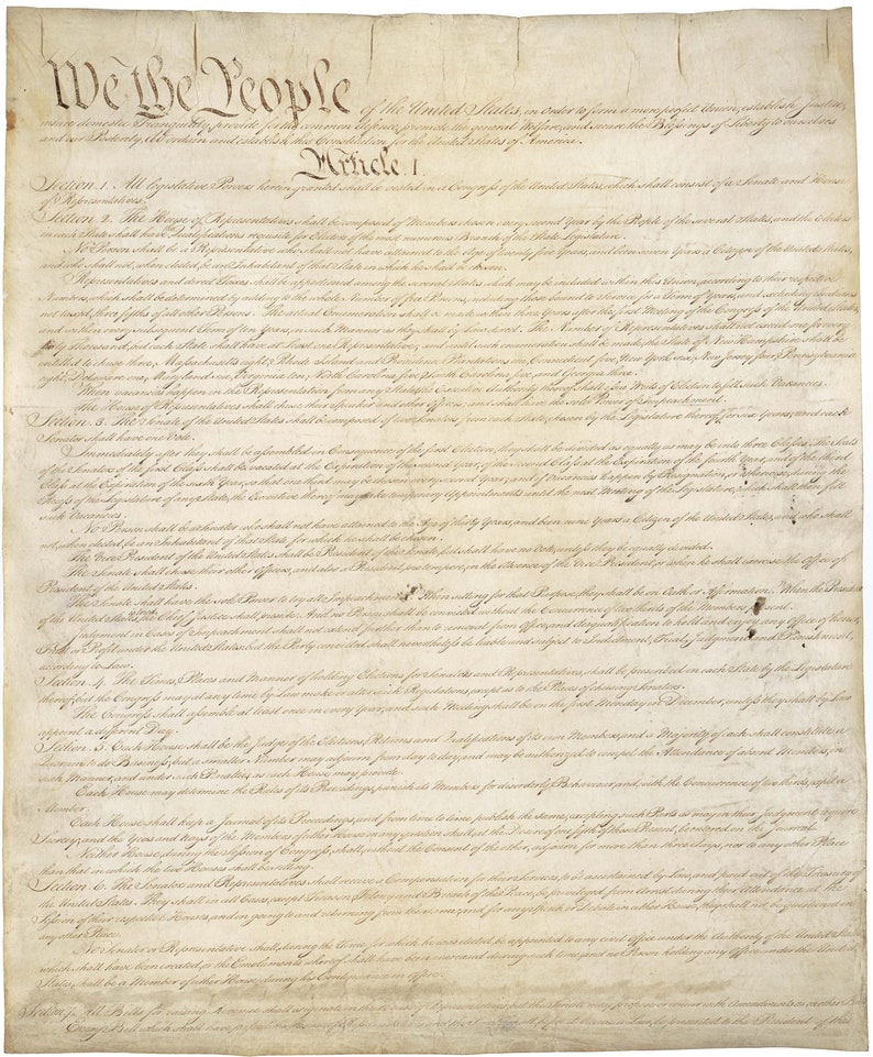 Puede incluir: Un primer plano del documento original escrito a mano de la Constituci&oacute;n de los Estados Unidos. El documento est&aacute; en papel envejecido con tinta marr&oacute;n y negra. El texto comienza con "We the People" e incluye el primer art&iacute;culo de la Constituci&oacute;n.