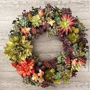 May include: A green, red, and yellow succulent wreath with a variety of textures and colors. The wreath is made of artificial succulents and is perfect for adding a touch of nature to your home decor.