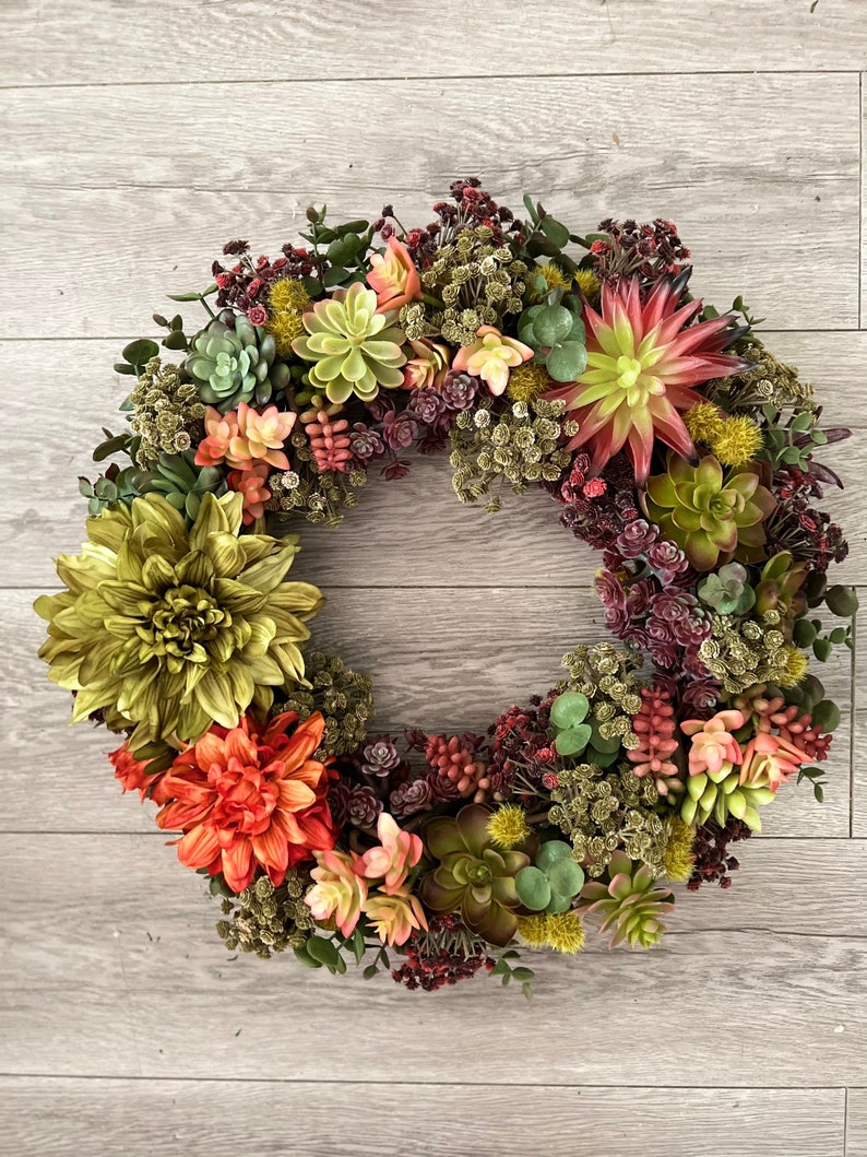 May include: A green, red, and yellow succulent wreath with a variety of textures and colors. The wreath is made of artificial succulents and is perfect for adding a touch of nature to your home decor.
