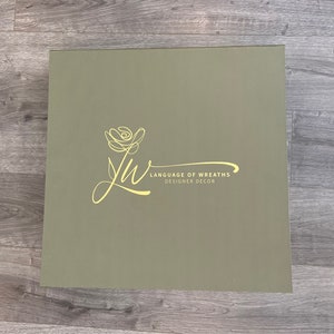 May include: A green box with a yellow floral design and the text "Language of Wreaths Designer Decor".