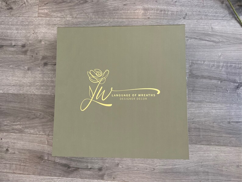 May include: A green box with a yellow floral design and the text "Language of Wreaths Designer Decor".
