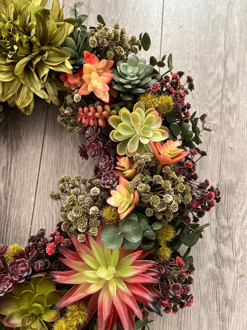 May include: A green and red succulent wreath with a variety of succulents and greenery. The wreath is made of artificial succulents and is perfect for adding a touch of nature to your home decor.