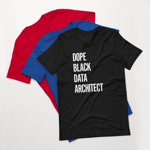 Puede incluir: Camiseta negra con texto blanco que dice "Dope Black Data Architect". La camiseta está doblada y se muestra sobre una camiseta azul y una camiseta roja.