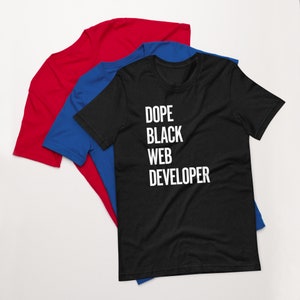 May include: Black t-shirt with white text that reads "Dope Black Web Developer". The shirt is layered on top of a blue t-shirt and a red t-shirt.