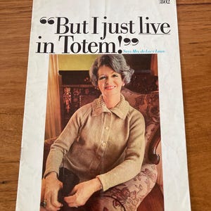 May include: A vintage knitting pattern booklet featuring a woman wearing a beige knitted cardigan and sitting in a floral armchair. The cover text reads "But I just live in Totem!" and "Says Mrs. de Lacy Lowe."