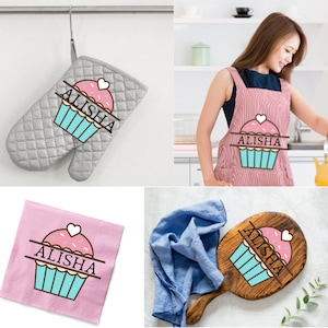 May include: A set of three kitchen items featuring a pink cupcake with a heart on top and the name "Alisha" written on it. The items include a gray oven mitt, a red and white striped apron, and a wooden cutting board.