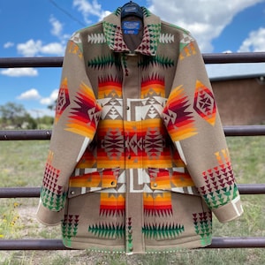 May include: A Pendleton wool jacket with a geometric pattern in shades of brown, orange, red, green, and white. The jacket has a button-up front and two pockets.