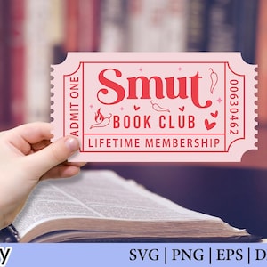 May include: A pink ticket with the words "Smut Book Club Lifetime Membership" in red. The ticket is held over an open book. The ticket has a serrated edge and the number 00630462.