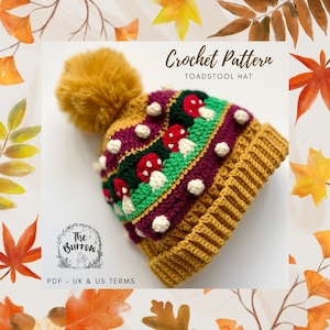 May include: Crochet pattern for a toadstool hat. The hat is mustard yellow with a burgundy, green, and white stripe featuring mushroom appliques. The hat has a fluffy mustard yellow pom pom.