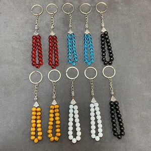 Puede incluir: Diez llaveros con cuentas de diferentes colores. Los llaveros están hechos de metal plateado y tienen una variedad de colores, incluyendo rojo, azul, negro, blanco y marrón.