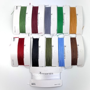 Op de afbeelding: Twaalf spoelen gewaxt koord in verschillende kleuren, waaronder rood, groen, blauw, bruin, zwart en wit. Elke spoel is gelabeld met "Accessories" en "Made in Turkey".