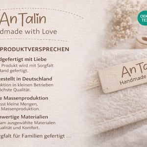 May include: A close-up of a cream-colored textile with the text "An Talin Handmade with Love" on a small tag. The image also includes text in German, highlighting product features like handmade quality and high-quality materials.