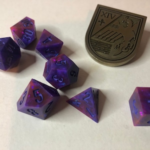 May include: A set of seven iridescent dice with purple and pink swirls. The dice are numbered 1 through 6 and are made of a translucent material. The dice are scattered on a white surface.