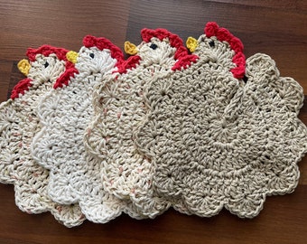 Pode incluir: Conjunto de cinco panos de cozinha de crochê em forma de frango, em bege e branco com detalhes vermelhos e amarelos.