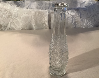Puede incluir: Un jarrón de vidrio transparente con un patrón de diamante. El jarrón es alto y delgado con una abertura estrecha.
