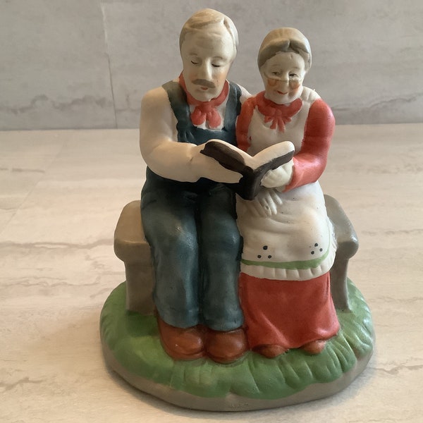 Vintage bisque elderly couple figurine of couple sitting on a bench reading a book together