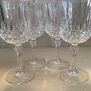 May include: Set of four clear glass wine glasses with a diamond pattern. The glasses have a tall stem and a wide bowl.