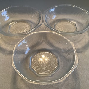 May include: Three clear glass bowls with a textured design. The bowls are octagonal in shape and have a raised, textured center.