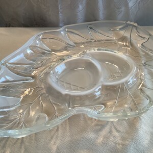 May include: A clear glass serving dish with a leaf design. The dish has two smaller bowls in the center.