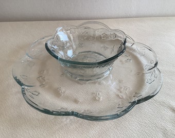 May include: A clear glass serving dish with a smaller bowl in the center. Both pieces have a scalloped edge and a floral design.