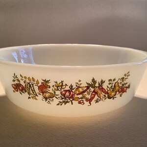 May include: White ceramic baking dish with a green, brown, and red vegetable design around the rim.