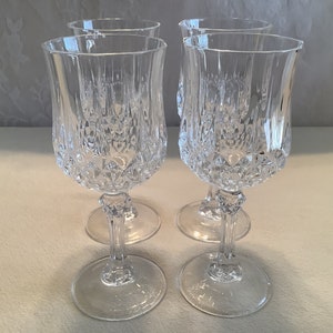 May include: Set of four clear glass wine glasses with a diamond-shaped pattern. The glasses have a tall, slender stem and a wide bowl.