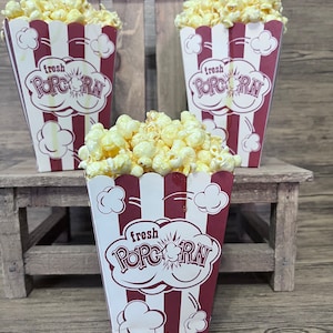 May include: Three red and white striped popcorn containers with the words 
