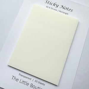 Könnte beinhalten: Ein rechteckiger, cremefarbener Haftnotizblock, 95 x 70 mm, auf weißem Papier. Auf dem Papier steht "Sticky Notes" und "The Little Boutique". Die Notizen sind transparent und enthalten 50 Blatt.
