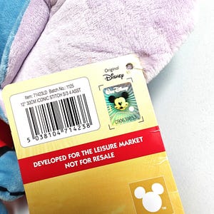 May include: A plush blue and purple Stitch toy with a Disney tag. The tag includes the text "12" 30CM ICONIC STITCH S/3 4 ASST" and "DEVELOPED FOR THE LEISURE MARKET NOT FOR RESALE". The tag also features the Disney logo.