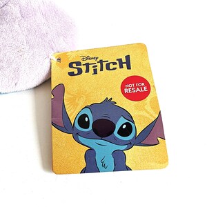 May include: A yellow tag featuring the Disney character Stitch with the word "Stitch" in blue and the text "NOT FOR RESALE" in a red circle. The tag has a cartoon image of Stitch.
