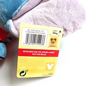 May include: A plush toy featuring a blue and purple character, with a tag that reads "12" 30CM ICONIC STITCH S/3 4 ASST." The tag also includes the text "DEVELOPED FOR THE LEISURE MARKET NOT FOR RESALE" and the Disney logo.