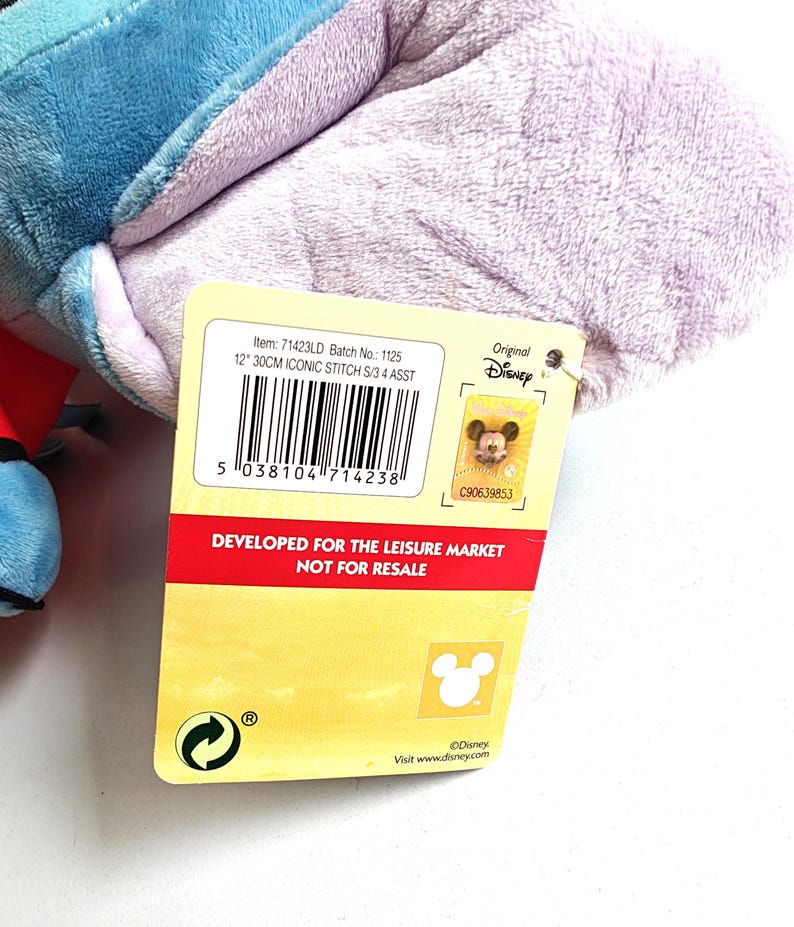 May include: A plush toy featuring a blue and purple character, with a tag that reads "12" 30CM ICONIC STITCH S/3 4 ASST." The tag also includes the text "DEVELOPED FOR THE LEISURE MARKET NOT FOR RESALE" and the Disney logo.