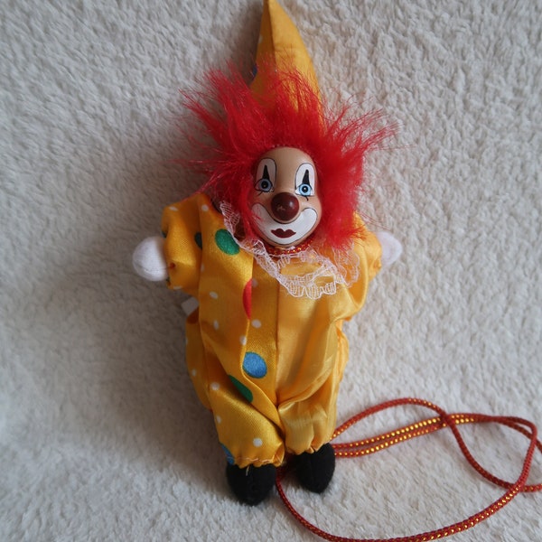 Decorative doll sad clown in a yellow suit, with red hair and a porcelain face. Hanging doll from Cologne, Germany. 17 cm high. Rare doll.