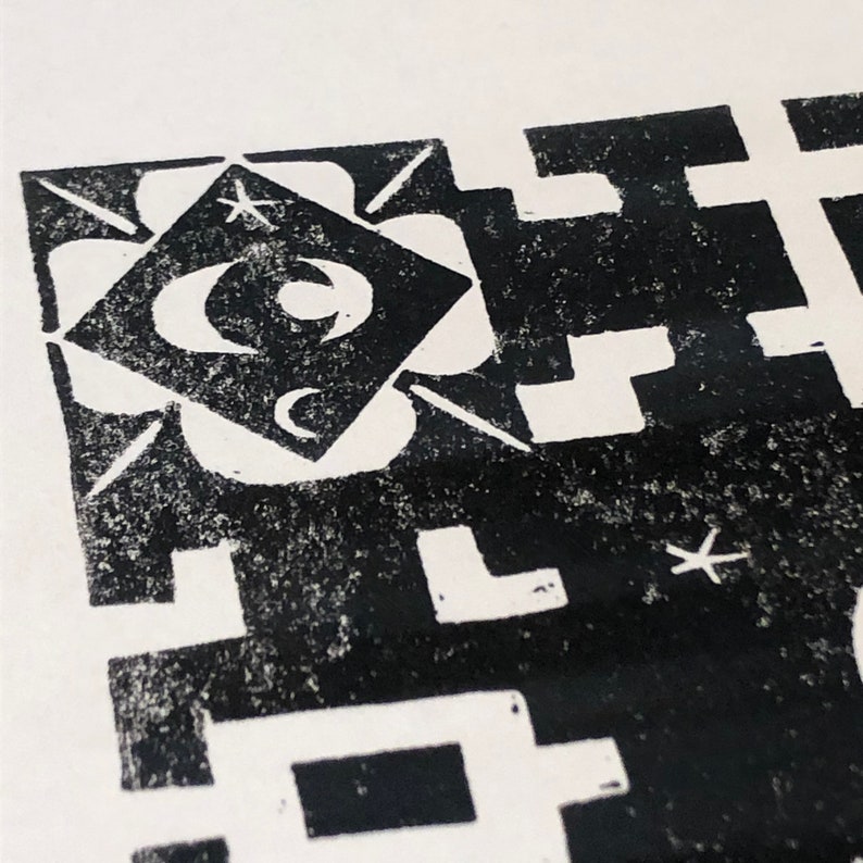 May include: Black and white abstract print with geometric shapes and a star design. The print features a square with an eye and crescent moon inside.