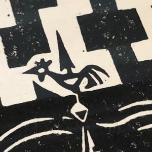 May include: Black and white linocut print of a rooster with a star on its head, standing on a platform with a pointed top. The rooster is facing the right side of the image. The background is a black and white checkered pattern.