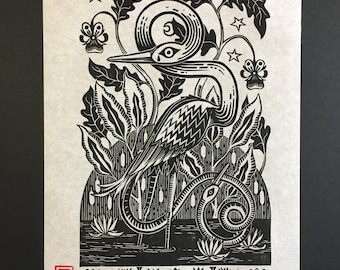 May include: Black and white woodcut print of a heron standing in a marsh with a snake wrapped around its leg. The heron has a long neck and beak, and the snake is coiled around its leg. The print is surrounded by a border of leaves and flowers.