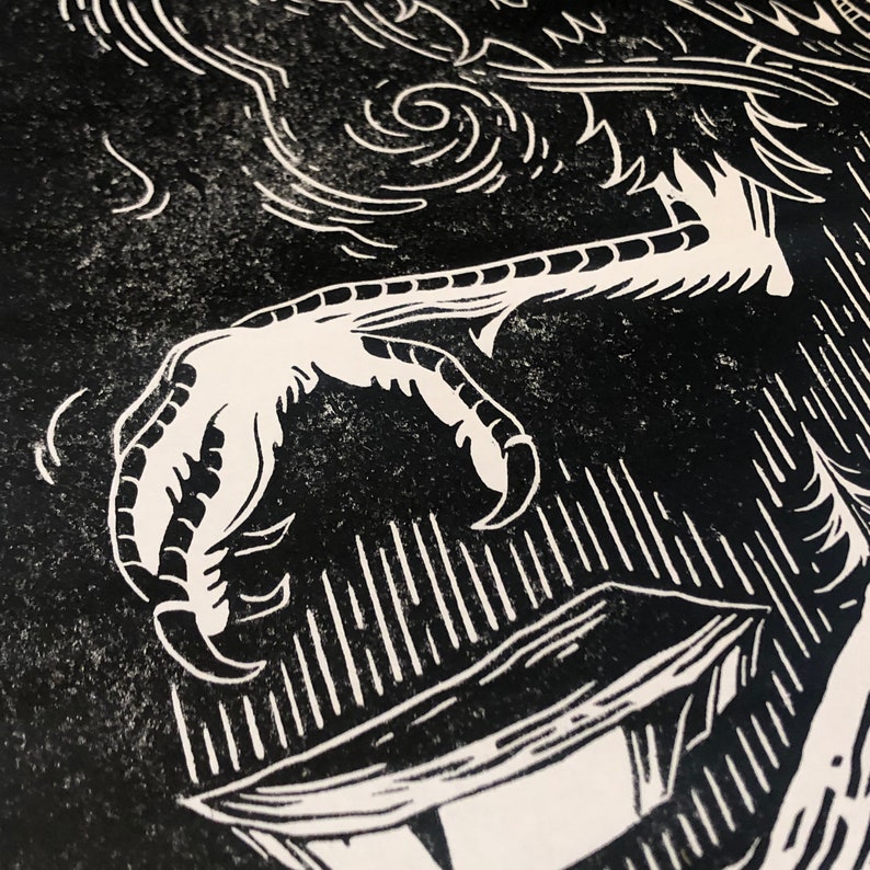 May include: Black and white linocut print of a bird's claw holding a box. The print has a textured, grainy look.