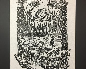 May include: Black and white woodcut print of a frog wearing a crown, surrounded by flowers and leaves. The print is signed "Nitamomorphose - CP. 2013".