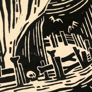May include: Black and white woodcut print of a house with a fence and a skull in the foreground. The house is made of wood and has a thatched roof. The fence is made of vertical planks. The skull is small and sits on the ground.