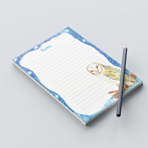 Könnte beinhalten: Ein blauer Notizblock mit einer weißen Eulenillustration und weißen Sternen am Rand. Der Notizblock hat liniertes Papier und den Text "Notes:" oben. Ein Bleistift liegt neben dem Notizblock.