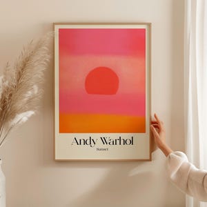 May include: A framed poster with a pink, orange, and yellow sunset illustration. The poster is titled "Andy Warhol Sunset".