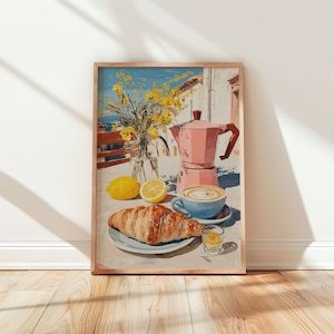 May include: A framed print depicts a sunny breakfast scene. A pink coffee maker, a blue cup of coffee, a croissant, and a glass of juice sit on a table. Yellow flowers in a vase and lemons complete the still life. The background shows a coastal view.