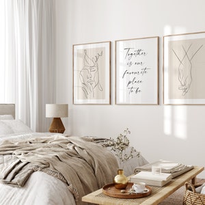 May include: Three minimalist line art prints in wooden frames on a white wall. The left print features a line drawing of a woman's face. The middle print has the text "Together is our favourite place to be". The right print features a line drawing of two hands holding each other.