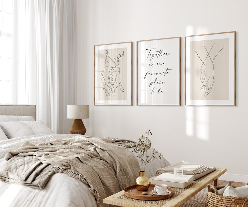 May include: Three minimalist line art prints in wooden frames on a white wall. The left print features a line drawing of a woman's face. The middle print has the text "Together is our favourite place to be". The right print features a line drawing of two hands holding each other.