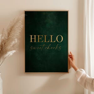 Puede incluir: Una impresión enmarcada verde oscuro con letras doradas que dicen "HELLO sweet cheeks".