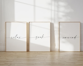 May include: Three framed prints with white backgrounds and black calligraphy. The prints read "relax", "soak", and "unwind".